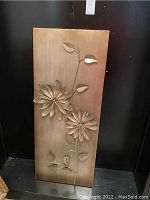 Front view of metal floral art panel hanging against black background, showing full piece and rectangular shape.