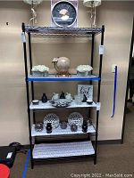 Front view of black metal shelving unit with decorative items on shelves.