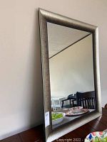 Frontal view of rectangular mirror showing reflective glass and textured gray frame.