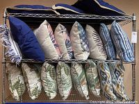 Shelving rack with two rows of decorative pillows showing various patterned and solid colors