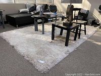 White shag rug shown in living room setup with black furniture and glass coffee table, displayed from different angles.