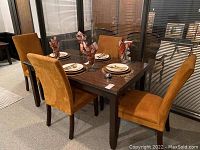 Dark wood rectangular dining table with four mustard suede upholstered chairs arranged around it.
