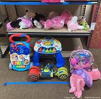 View of plush toys, learning walker, musical learning toy, Hot Wheels Ballistic Racer, rollerblades in clear case