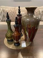 Four decorative vases displayed on round gold vinyl placemat on sofa background