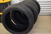Four Pirelli winter tires stacked on concrete floor showing full set