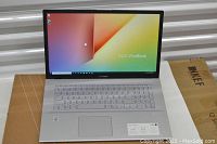 Front-open view showing display powered on with ASUS VivoBook wallpaper and full-size backlit keyboard.