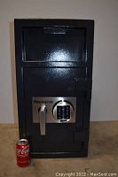 Front view of dark grey powder-coated steel depository safe with electronic keypad and lever handle. Coca-Cola can placed for scale.