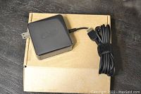 Black power adapter and attached cord coiled with Velcro on top of plain cardboard box.