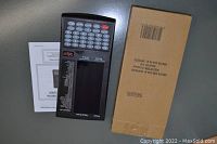 Photo of the digital dart scorer device, its manual, and original cardboard box on a gray surface.