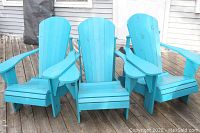 Three teal wooden Adirondack chairs on deck, front view