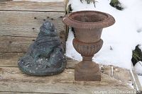 Cast iron frog garden ornament and planter shown on wooden surface with snow background.