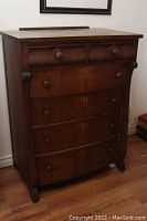 Full front view of the antique 6 drawer wooden dresser with round wooden knobs and a dark wood finish.