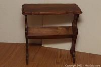 Front view of the antique wooden end table featuring curved legs and bottom shelf