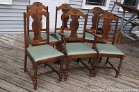 Front view showing fully assembled chairs, including two armchairs and four side chairs, all with carved wooden backs and upholstered seats in light green fabric.