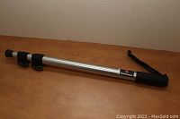 Full view of the collapsed aluminum monopod with foam grip and wrist strap lying on a wooden surface.