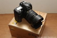 Nikon D70 DSLR camera on original box showing camera body with attached lens and lens hood