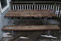 Front view of entire picnic table on deck, showing tabletop and benches