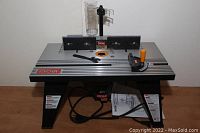 Full front view of router table with fence, clear dust shield, adjustment wrench on top, motor below