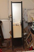 Front view of the Ikea standing mirror showing the full-length reflective surface and lower shelf storage rack.
