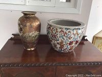 Front view of the two ceramic vessels on a wooden surface, showing the tall vase and large pot side by side.