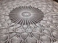 Full view of one round white crocheted tablecloth laid flat showing central spoke pattern and surrounding motifs