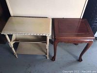 Two decorative end tables side by side, one off-white rectangular with carved details and lower shelf, one dark wood square with curved legs