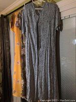 Three plus size dresses hanging on hangers, showing colors, patterns, sleeve types and lengths