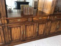 Front view of the wooden hutch cabinet showing drawers and cabinet doors with brass handles.