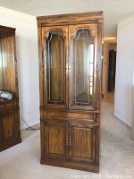 Front view of the wooden Sklar-Peppler hutch with glass doors, brass hardware, and wood panel doors below.