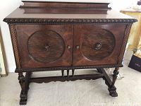 Front view of sideboard showing carved trim, two doors and raised backboard