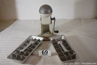 Front view of two aluminum ice cube trays and Ice-O-Matic ice crusher showing overall condition and design.