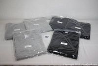 Six folded sweatshirts in original bags on table, 3 gray and 3 black Hanes sweatshirts shown.