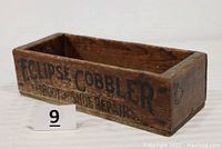 Front and side views of the wooden Eclipse Cobbler toolbox with clear black lettering advertising cobbler and repair services.