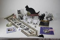Full lot of cat-themed items including blackboard coat rack, stone cat, books, mug, candle holder and banner
