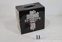 Black original box with Death Note logo on front and top handle, showing some wear and damage to the lid.