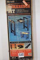 Image of original box front showing black steel workbench frame with drawer and tool rack, no top included, shows complete kit illustration and branding