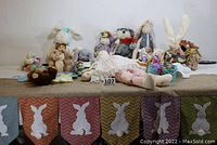 Wide shot of lot showing all plush bunny rabbits, cloth doll, Easter basket, eggs, and paper garland with bunny silhouettes.