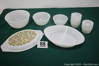 Full set of milk glass Fire King and Glasbake items including three mixing bowls, seven small bowls, divided casserole dish (missing lid), and Pyrex lid with gold pattern.