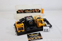 Full view of the power sharpener placed on a black base with carrying case and instruction manual