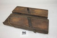 Pair of vintage wooden cabbage cutters side by side on white surface, showing top surfaces with metal blades and overall wood condition