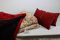 Full view of floral bedspread, burgundy throw partially folded, and two matching burgundy pillows.