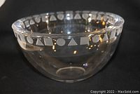 Clear crystal bowl showing etched geometric pattern around upper rim, placed on dark background to highlight design and crystal clarity.