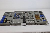 Opened gray molded plastic tool case showing hammer, adjustable wrench, pliers, multiple sockets, screwdriver with bits, level, and tape measure