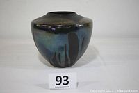 Front angle view of art pottery urn vase showing glossy blue and black glaze with abstract dripping patterns.