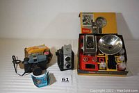 Full view of the three cameras including Kodak Duaflex III in original box with flash, Argus 40 camera, and Stellar camera with blue colored manual.