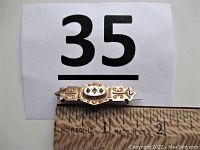 Full view of the bar brooch alongside a ruler showing length approximately 1.5 inches.