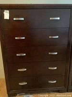 Front view of brown 5 drawer dresser with silver metal handles showing overall condition.