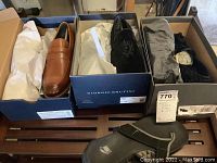 Four pairs of men's shoes in their boxes: Cole Haan loafers, Giorgio Brutini dress shoes with black embroidered design, Stacy Adams black dress shoes, and Nike flip-flops.