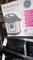 Photo of Instant Pot IP-DUO60V2 in box displayed on top of Toshiba microwave oven