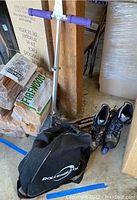 Razor scooter with purple foam handle grips, black deck, and carrying bag alongside items